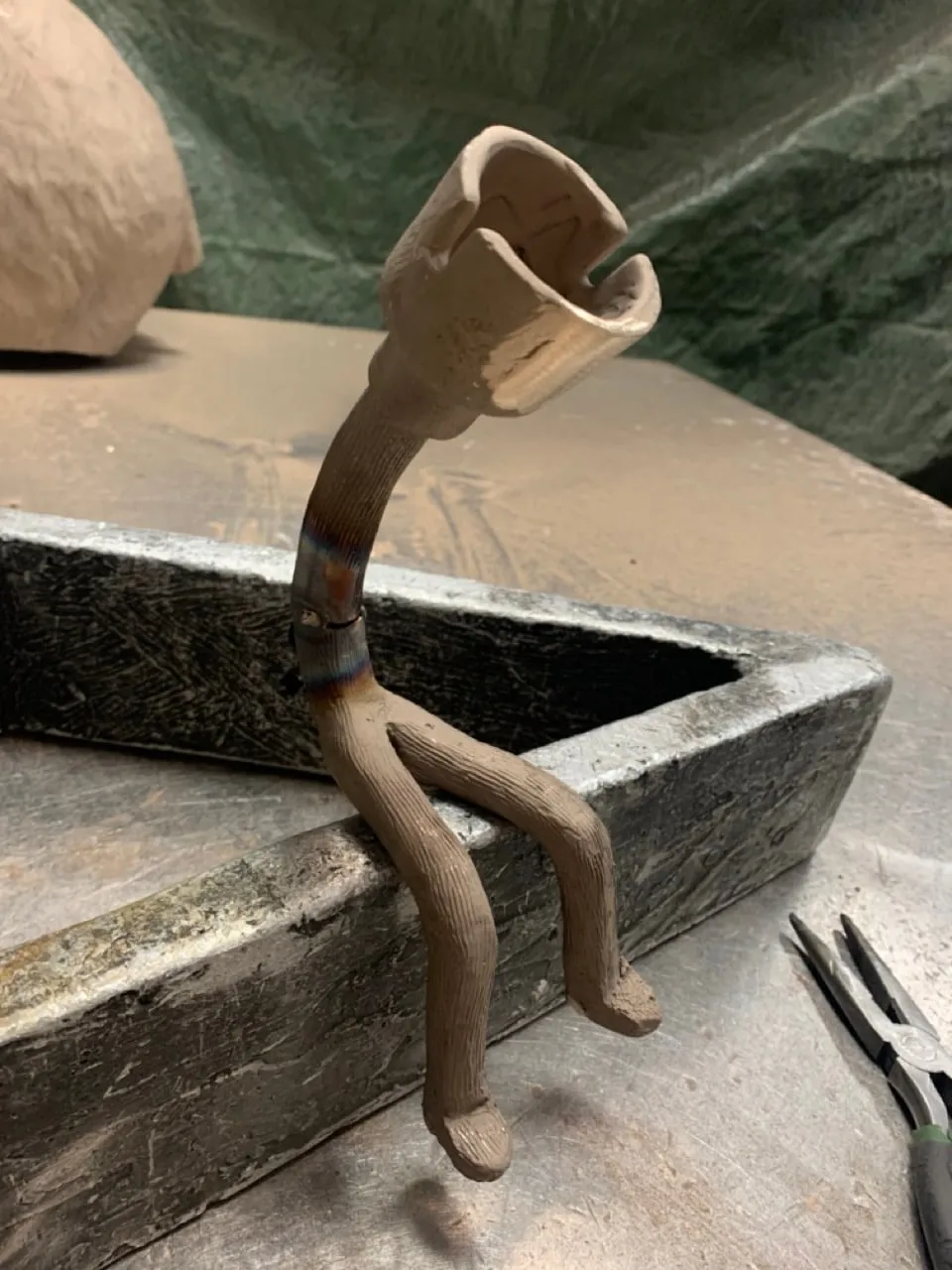 The cast figure on a foundry bench, heat colouring at the joins